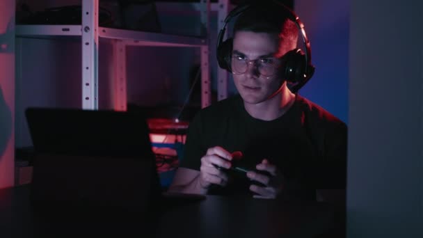 游戏的乐趣 网络娱乐 受鼓舞的男人在家里用无线游戏平台在黑暗的工作场所玩电子游戏 — 图库视频影像