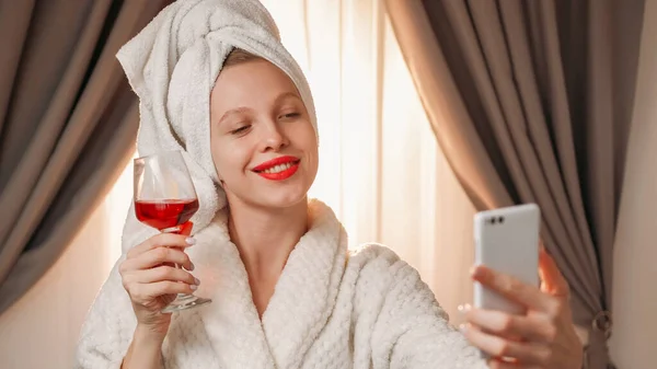 オンラインドリンク ビデオ通話 リモートお祝い 幸せな笑顔の女性でバスローブ挨拶でアルコール赤ワイングラストースト自宅で電話カメラで話すコピースペース付き — ストック写真