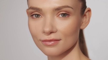 Kusursuz bir yüz. Cilt sağlığı. Güzel, kendine güvenen, doğal makyajlı, kendine güvenen, güzel bir kadın. Yüzü nemden tatmin olmuş. Bej arka planda izole edilmiş..