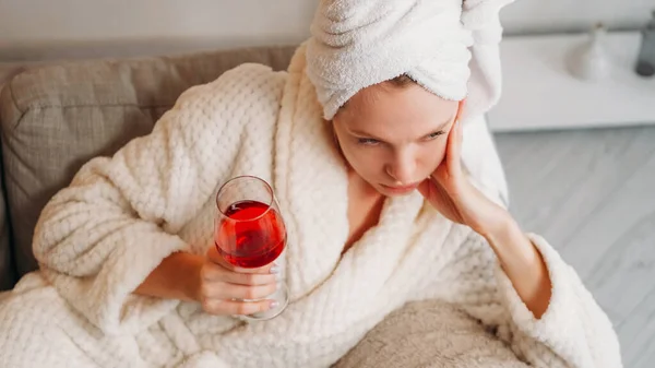 飲み物だ うつ病だ 週末は退屈だ お風呂の後にソファで一人でアルコール赤ワインのガラスとバスローブの悲しい浸透女性を動揺 — ストック写真