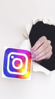 Kharkiv, Ukrayna - Haziran 04, 2020: Dikey video. Instagram logosu. Sosyal medya. Beyaz döngüde mobil uygulama simgesini gösteren bir kağıt deliğinin içindeki kadın etkili el.