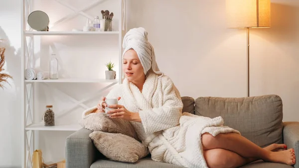 ホームスパ お茶療法 リラックス 女性用バスローブタオルとホットドリンクマグカップシャワー後ソファの上に光のインテリアでフリースペース — ストック写真