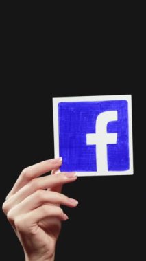 Kharkiv, Ukrayna - 12 Mayıs 2020: Dikey video. Facebook ikonu. Sosyal medya. Siyah boş arkaplanda izole edilmiş kadın el uygulama işareti gösteriliyor.