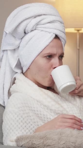 垂直录像 可悲的周末 家庭沉思 星期天的孤独穿着浴衣 闷闷不乐的女人在沙发上喝茶 — 图库视频影像