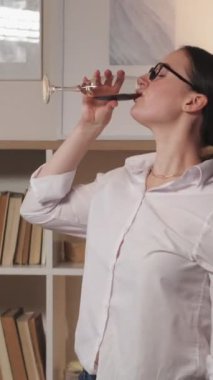 Dikey video. Alkol partisi. Ev eğlencesi. Pozitif yaşam tarzı. Tasasız bir hafta sonu. Neşeli kadın kadehle dans edip yalnız başına şarap içiyor..