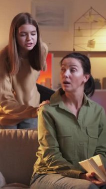 Dikey video. Laptop çalış. Beklenmedik bir hediye. Kitap okuyan bir kadın modern dizüstü bilgisayara akşam odası hazırlamaya geliyor..