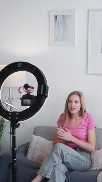 垂直录像 女性博客 部落格的建议 快乐而情绪高涨的年轻女子在家里带着彩灯的白色房间里 用三脚架对着摄像机记录着自己的内容 — 图库视频影像