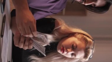 Dikey video. Para yönetimi. Aile bütçesi. Harcama hesabı. Varlıklı, çok kültürlü bir çift 100 Amerikan Doları nakit tasarrufu hesaplıyor..