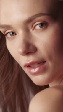 Dikey video. Doğal güzellik. Parlak bir yüz. Organik yüz kozmetikleri. Cilt bakımı. Çıplak makyajlı genç bir kadın mükemmel parlayan bir ten.