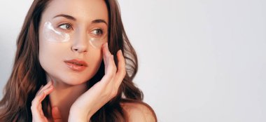 İyileşme bantları. Göz teması altında. Yaş maskesi. Yüz kozmetolojisi. Temiz ciltli güzel bir kadın beyaz arka planda izole edilmiş kolajen pedlerle kırışıklıkları azaltıyor..