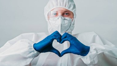 Enfeksiyon uzmanı. Sağlık hizmetleri koruması. Aşk jesti. Tıbbi malzemelerde çalışan kadın doktor virüs uzmanı. Gri arka planda kalp izleri var..