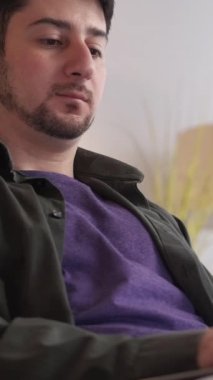 Dikey video. Çalışan programcı. Görev konsantrasyonu. Serbest geliştirici. Düşünceli, odaklanmış, kafası karışmış, uzaktan kumandalı bir çalışan evde dizüstü bilgisayarla yazı yazıyor..