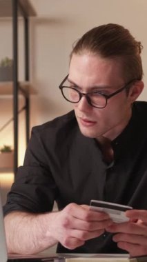Dikey video. Banka dolandırıcılığı. Finansal dolandırıcılık. Para transferi riski. Hayal kırıklığına uğramış bir iş adamı, iş yerindeki dizüstü bilgisayarında kişisel kredi kartı bilgilerini kullanarak online ödeme yapıyor..