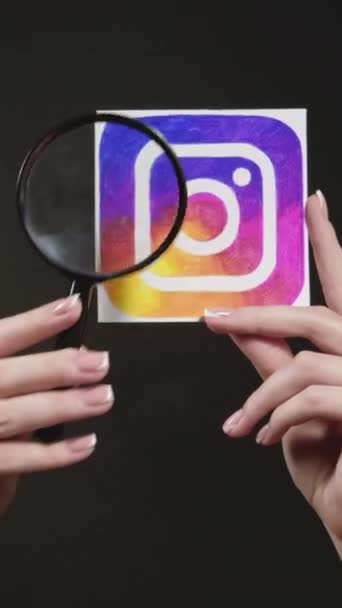 Harkiv ウクライナ 2020年5月12日 垂直ビデオ Instagramのアイコン ソーシャルメディア検索 女性の手黒ループに隔離された虫眼鏡でアプリのロゴを探索 — ストック動画