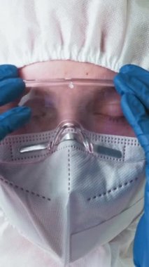 Dikey video. Çevre bilimcisi. Enfeksiyon felaketi. Kadın ekoloji uzmanı koruyucu tıbbi ekipman gözlüğünü çıkarıyor maske eldivenleri.