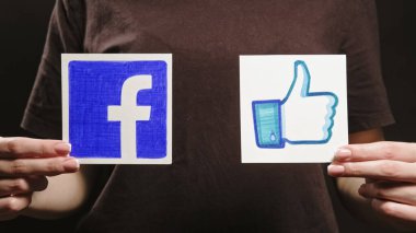 Kharkiv, Ukrayna - 12 Mayıs 2020: Facebook benzeri. Sosyal ağı takip et. Kadın elleri uygulama simgesini tutuyor. Koyu boşlukta dizayn işareti..