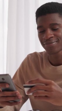 Dikey video. Gadget Bankası. Çevrimiçi ödeme. Para transferi. Faturaları ödeyen memnun bir adam. İnternetten alışveriş yapıyor. Evde kredi kartıyla..