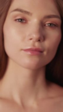 Dikey video. Cilt kılı sağlığı. Dikkat prosedürü. Doğal güzellik cilt bakımı. Çekici, oyuncu, genç bir kadın. Yüzü pürüzsüz, pırıl pırıl, çıplak..