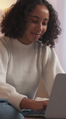 Dikey video. İnternet araştırması. Uzaktan kumanda. Çevrimiçi iletişim. Diz üstü bilgisayarda arkadaşıyla sohbet eden mutlu bir kadın. Hafta sonunun keyfini çıkarıyor..