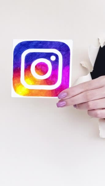 ハリコフ ウクライナ 2020年6月4日 垂直ビデオ ソーシャルネットワーク Facebook Instagramのを共有する画期的な紙の穴の女性の手白の背景にTiktokのTwitterメディアアイコン — ストック動画