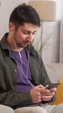 Dikey video. Telefon sorunu. Kötü internet. Mobil oyun. Evdeki kanepede bağlanma hatasından rahatsız olan, kulaklıklı sabırsız öfkeli adam atmaca oynuyor..