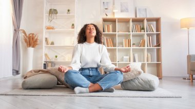 Kadın meditasyonu. Evde rahatla. Huzurlu bir zihin. Nilüfer çiçeğinde oturan sakin kadın oturma odasında yoga yapıyor..