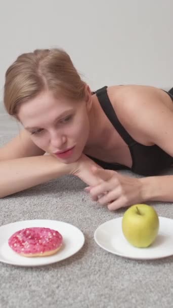 垂直ビデオ 不健康な食生活 ジャンクフード 甘い中毒 緑のリンゴの果物の代わりにおいしいドーナツデザートを選ぶ幸せな女性 — ストック動画