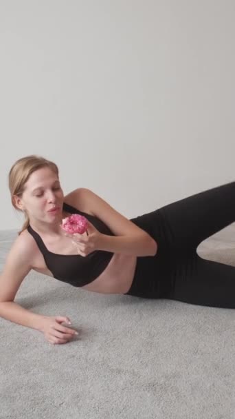 垂直录像 卡路里燃烧运动训练 减肥健身锻炼 松懈的女运动员在地板上做体育锻炼 享受甜食甜甜圈甜点 — 图库视频影像