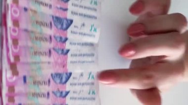 Dikey video. Para geliri. Finansal bütçe. 200 Ukrayna Hryvnia kağıt para yığını kadın eli sayıyor..