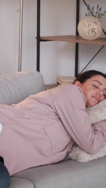 垂直录像 睡觉的时间 女儿的照顾 可爱的女孩盖着格子花妈妈睡在沙发上 周末睡在明亮的房间里 — 图库视频影像