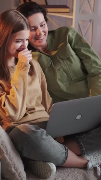 垂直ビデオ 家族のインターネット ビデオ監視 幸せな母親娘笑います座ってソファ見て面白い映画上のラップトップ楽しいですレジャー一緒に家のインテリア — ストック動画