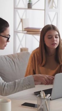 Dikey video. Evde özel ders. Sınav hazırlanıyor. Genç kız öğretmeniyle ders çalışıyor. Ev içinde dizüstü bilgisayar kullanıyor..