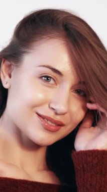 Dikey video. Cilt bakımı. Kolajen tedavisi. Yüz prosedürü. Kadın güzelliği. Taze, ışıl ışıl yüzü olan, saçlarına dokunan zarif, mutlu bir poz veren kadın..
