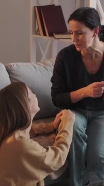 Dikey video. Kızımın desteği. Ebeveyn bağlantısı. Anne genç kız evdeki kanepede birlikte oturarak samimi bir konuşma yapıyor..