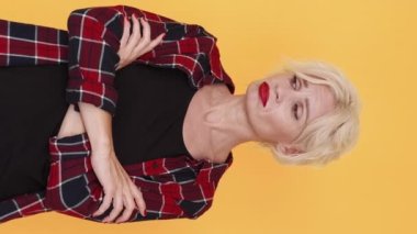 Dikey video. Hayal kırıklığına uğradım. Üzgün kadın. Üzücü duygular. Üzgün orta yaşlı bir kadın kederini dile getiriyor. Sarı göğüste el ele tutuşuyor..