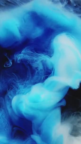 垂直ビデオ インクの水のショット カラー蒸気雲 水中塗料混合物 濃い抽象美術の背景に青い白い輝くもやの波の動き — ストック動画