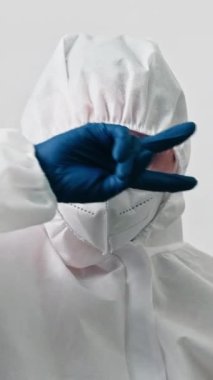 Dikey video. Doktor kutlaması. Tıbbi zafer. Başarıyı iyileştir. Mutlu sağlık uzmanı kadın maske takıyor mavi eldivenler gri arka planda tek başına dans ediyor..