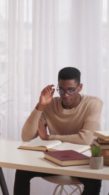 Dikey video. Eğitim stresi. Zor sınav. Zor bir çalışma. Gözü ağrıyan yorgun bir adam. Kitap okuyor. Ev ödevi araştırması için çalışma masasının fotokopisini çekiyor..