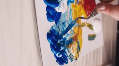 Dikey video. Sanat süreci. Kadın ressam. Resim okulunda. Resim odası yaratmak için spatulayla boyaları karıştıran tanınmamış bir kadın..