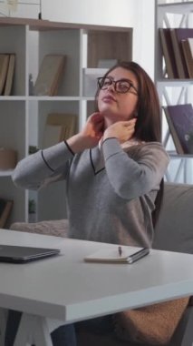 Dikey video. İşini bitir. Yorgun bir kadın. Isınma egzersizleri. Yorgun bir kadın dizüstü bilgisayarı kapatırken gergin hissediyor..