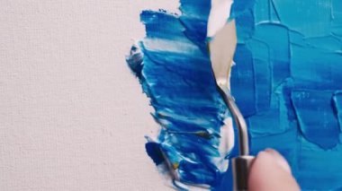 Dikey video. Sanat eseri yaratımı. Kadın ressam. Manzara resmi. Beyaz tuvale spatula ve renkli resimlerle resim yapan tanınmayan bir kadın..