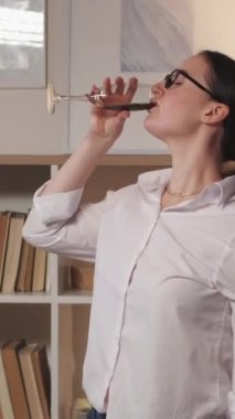 Dikey video. Alkol partisi. Ev eğlencesi. Pozitif yaşam tarzı. Tasasız bir hafta sonu. Neşeli kadın kadehle dans edip yalnız başına şarap içiyor..
