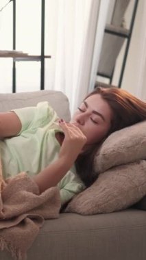 Dikey video. Ateş hastalığı. Hasta kadın. Üşütürüm. Ekoseyi örten kötü bir kadın gibi hissediyorum. Termometre lambasının iç tarafında yüksek sıcaklık görüyorum..