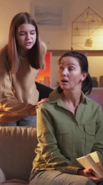 Dikey video. Laptop çalış. Beklenmedik bir hediye. Kitap okuyan bir kadın modern dizüstü bilgisayara akşam odası hazırlamaya geliyor..