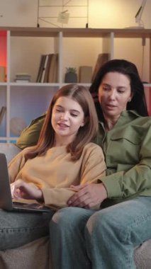 Dikey video. Koltuk bakınıyor. Aile ağları. Gülümseyen genç kız internetten alışveriş yapıyor. İnternette sörf yapıyor..