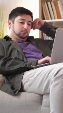 Dikey video. Uzaktan kumanda. İş yorgunluğu. Gadget bağımlılığı. Çalışmaktan yorgun düşmüş serbest çalışan işkolik dizüstü bilgisayarda yazarak evde kanepede kestiriyor..