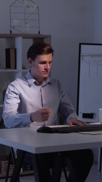 垂直ビデオ 遅い仕事だ 忙しい男だ コンピュータ技術 光の影の部屋のインテリアでコーヒーを飲むスマートカジュアルな男 — ストック動画