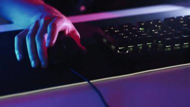 Gece işi. Oyun yarışması. Uzaktan kumanda. Fare sörfü yapan erkek eller çevrimiçi sosyal ağlarda geziniyor video oyunları oynuyor karanlık neon ışığı.