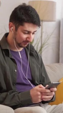 Dikey video. Telefon sorunu. Kötü internet. Mobil oyun. Evdeki kanepede bağlanma hatasından rahatsız olan, kulaklıklı sabırsız öfkeli adam atmaca oynuyor..