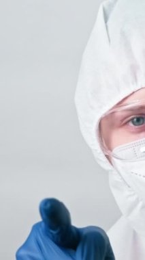 Dikey video. Tıp doktoru. Hoş geldin jest. Sağlık kontrolü. Gri arka planda parmak işareti yapan kadın doktor..